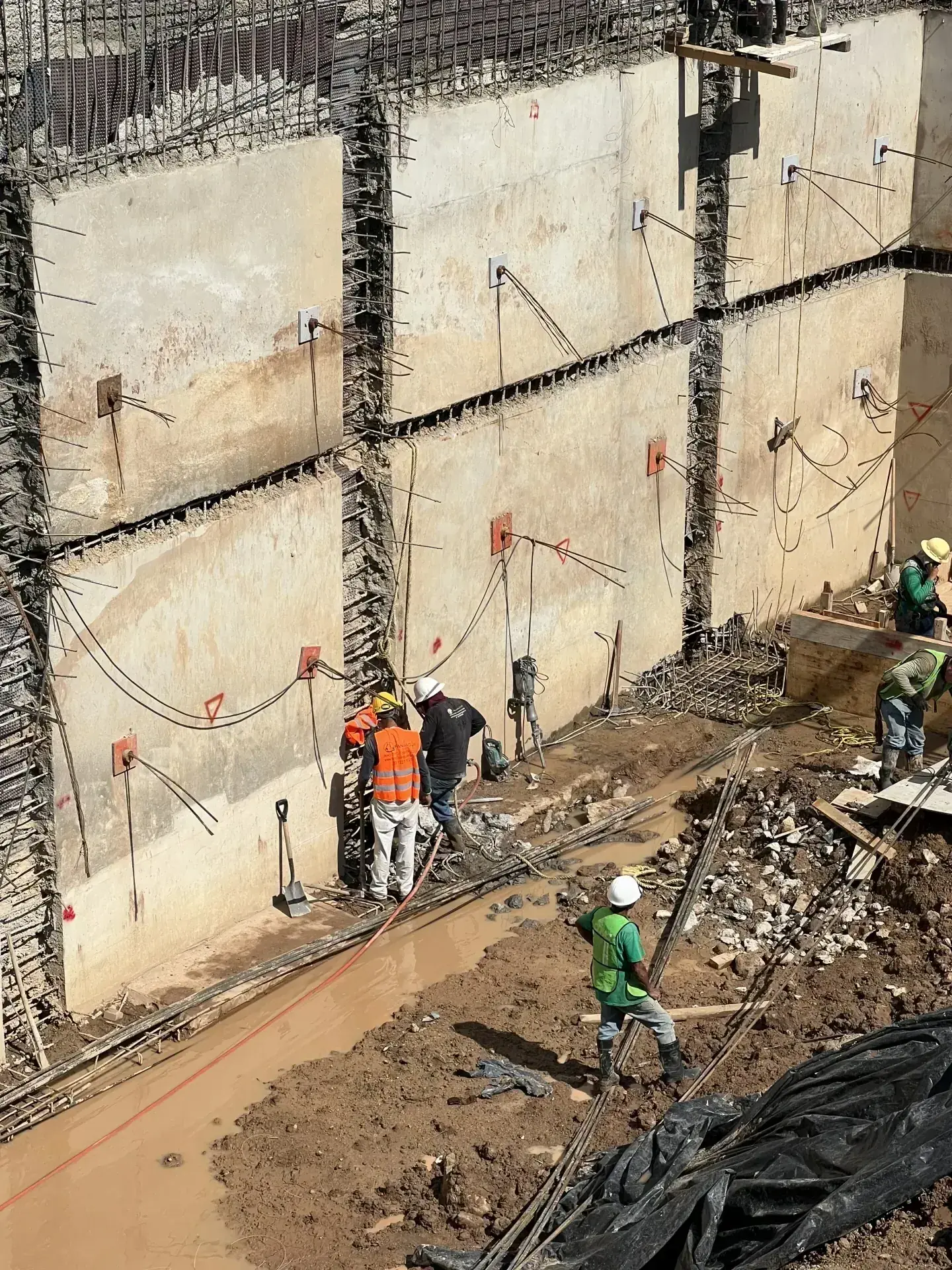 Vista aérea de una excavación profunda con muros de contención y trabajadores en obra civil en Zapopan.