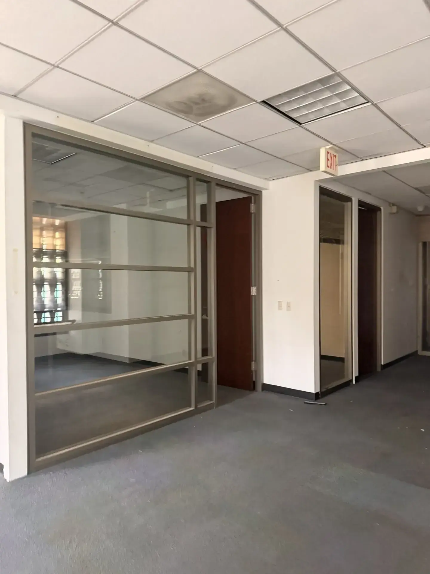 Interior de oficina vacía con alfombra gris y paredes blancas, lista para demolición o remodelación en Zapopan.