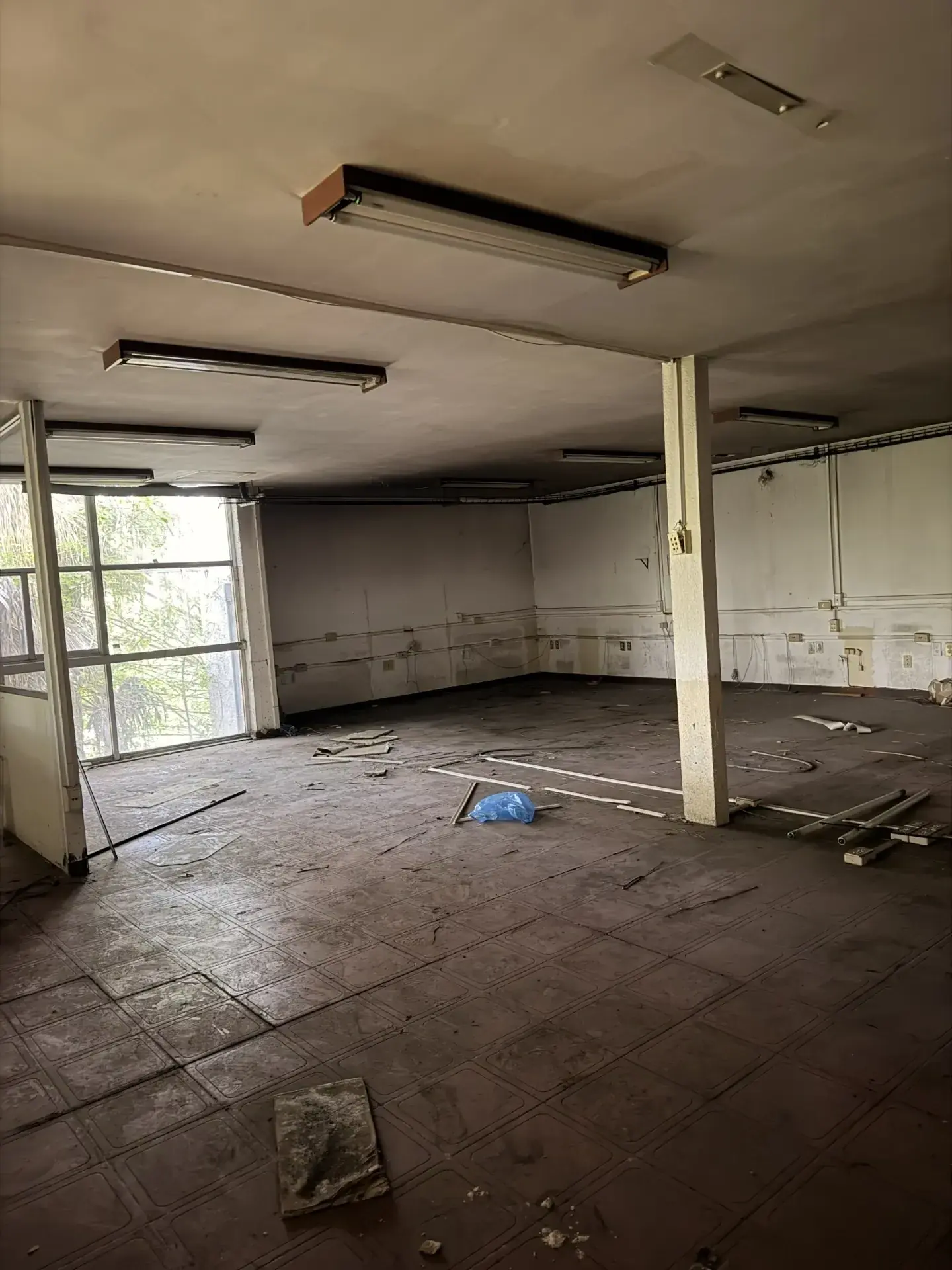 Interior de un local comercial vacío y sucio con escombros en el suelo, listo para demolición o limpieza en Zapopan.