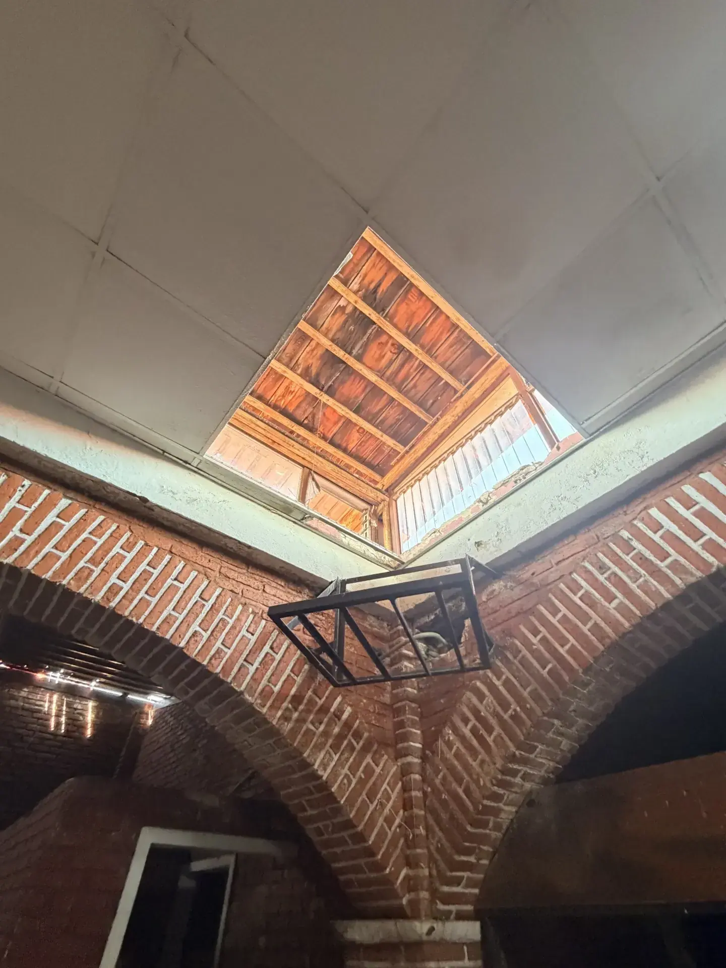Vista interior de un edificio con arcos de ladrillo y un tragaluz, mostrando detalles de obra civil en Zapopan.