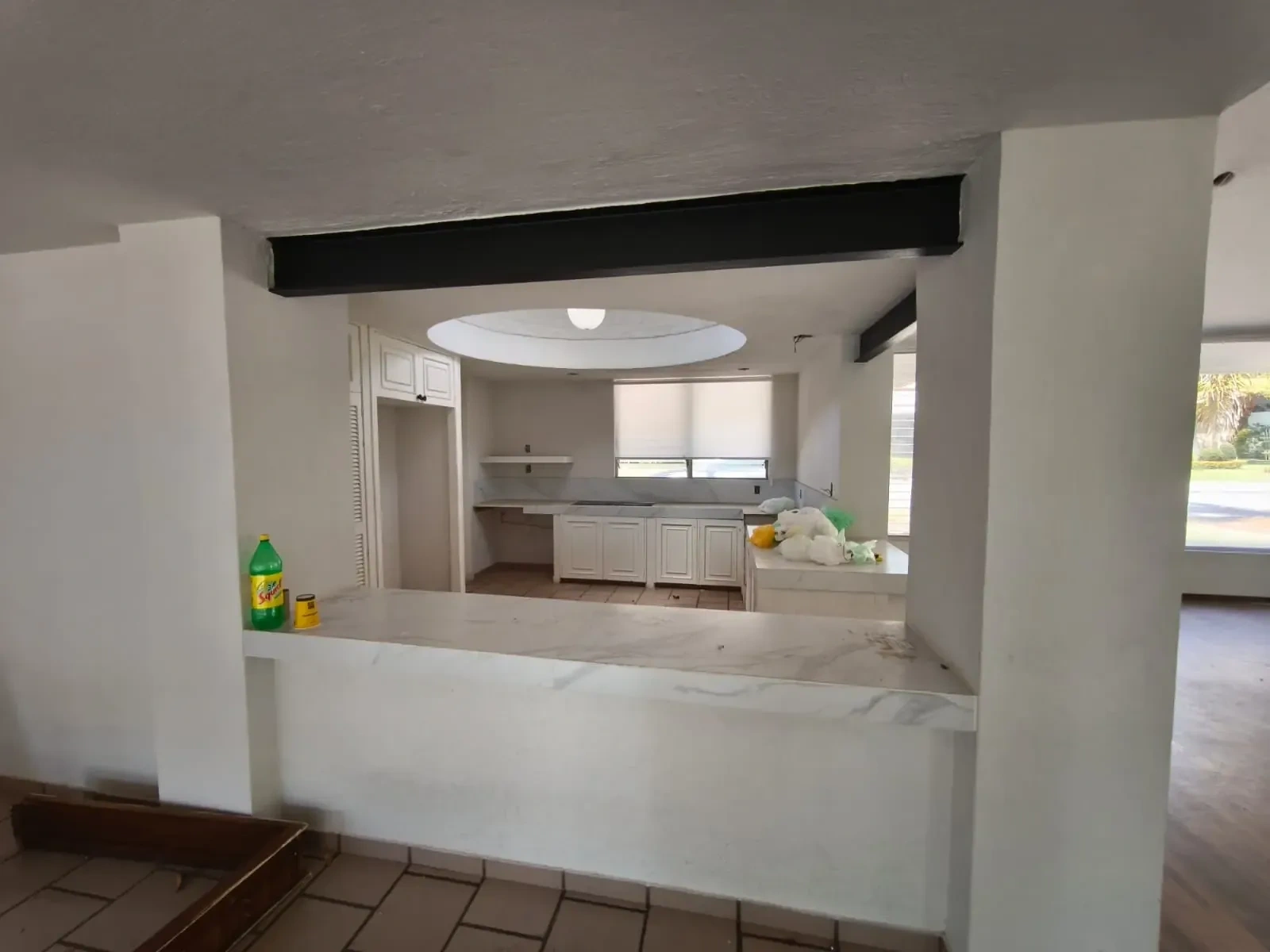 Espacio interior con cocina de gabinetes blancos y barra, viga expuesta, ideal para remodelaciones en Zapopan.